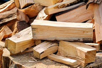 A pile of chopped firewood logs ready for the winter. Cut logs fire wood. Hardwood, wood and lumber industry. Heating season, winter season. Renewable resource of energy. Environmental concept.