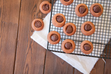 Chocolate ganache thumbprint cookies on a wire rack on a wooden background.