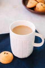 Cup of coffee and thumbprint cookies on a white background.