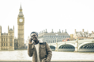 African american young man using mobile smart phone at Thames riverbank in London - Hipster guy...