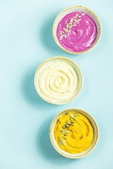 Snacks in the form of sauces from carrots, beets and hummus from chickpeas. in bowls on a contrasting blue background