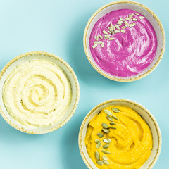 Snacks in the form of sauces from carrots, beets and hummus from chickpeas. in bowls on a contrasting blue background
