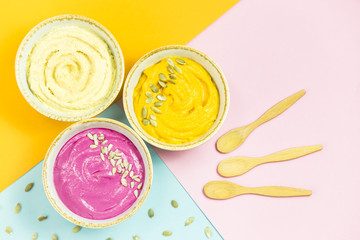bright appetizers in the form of vegetable sauces and hummus of chickpeas on a combination multicolored background