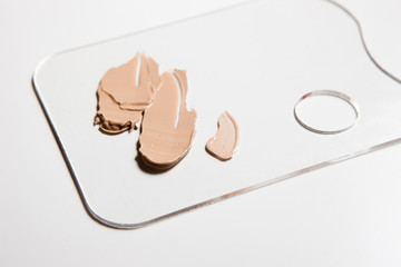Cosmetic foundation swatch on palette on white background, close up. Professional make up product for face and concealer samples