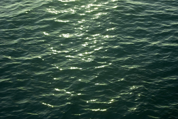 background, texture: sea water surface with sunlight reflections in the evening illumination