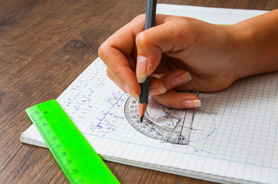 schoolgirl solves the problem of mathematics. school, education, people and learning concept - close up of student or woman hands with ruler and pencil drawing line in notebook