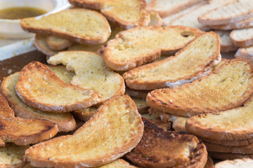 Fototapeta na wymiar Preparing Slices of Grilled Bread with Olive Oil, Italian Snack