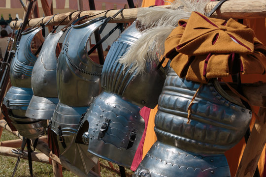 Hanged Metallic Armors in Line in front of Red and Yellow Tent