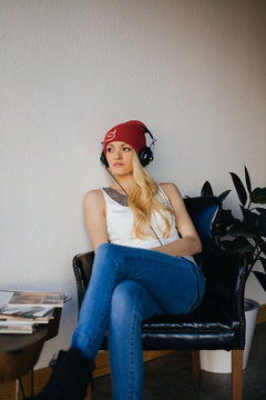 Pretty Blond Woman in a Beanie and Headphones Listening to Music