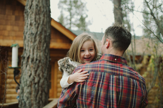 father carrying excited daughter into cabin