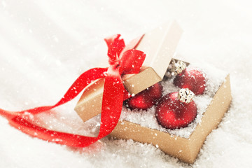 Beautiful red classic baubles or christmas decoration in a gift box with snow, christmas concept
