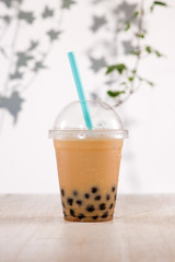 Homemade milk bubble tea in plastic cups on table.