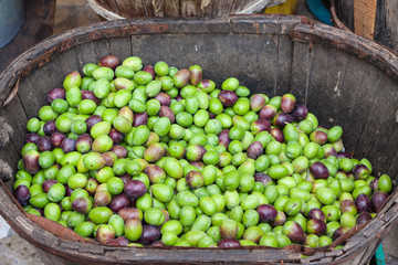 Freshly harvested green and black olives in a wooden basket for sale at Sineu market, Majorca, Spain
