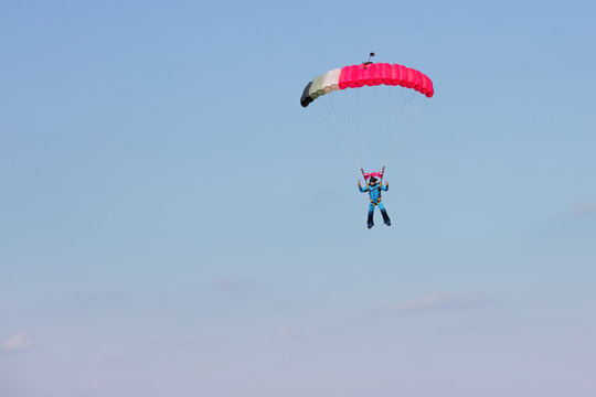skydiver on pink parachute on background blue sky