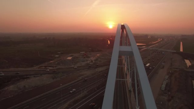 New built bridge on a highway with traffic, The Netherlands, aerial shot sunset