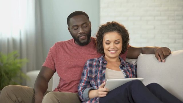 Married couple choosing furniture for new apartment, using mobile shopping app