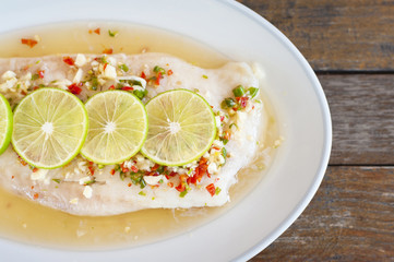Steamed fish in lime on wooden table brown with thai style