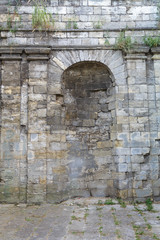 Ancient stone wall. Brickwork. Sealed archway. Vertical.