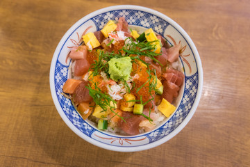 Sushi don, Raw Salmon sashimi, egg and Salmon eggs on steamed rice with Wasabi and Pickled Ginger bowl on the wooden table, Japanese food