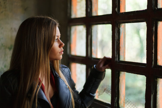 Pensive blonde woman next to a vintage windows