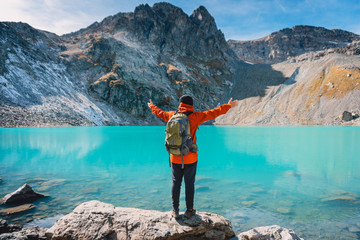 Happy Hiker looks at the mountain lake. Beautiful turquoise lake in the mountains.
