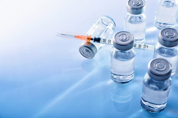 Vials and syringe on blue table top elevated - obrazy, fototapety, plakaty