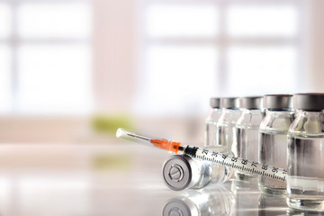 Vials group and syringe on white table with background windows