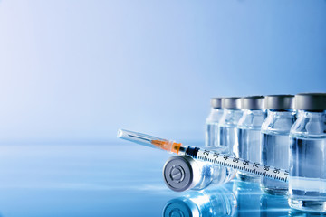 Vials group and syringe on table with blue background
