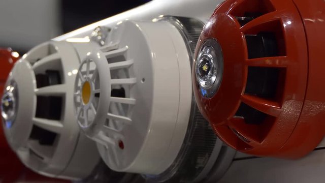 Close up of red and white fire and security alarm sounders with led indicators flashing