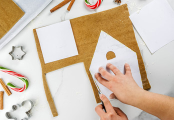 Preparing for Christmas, a person, hands in the frame, makes a gingerbread house. Cutting on a...