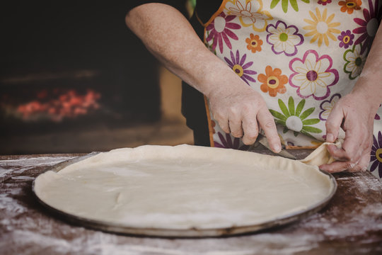 Old female hands shaping the pizza dough