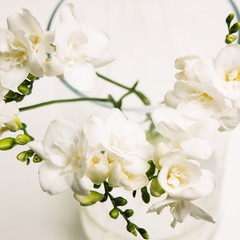 Fototapeta na wymiar Close up of white bunch of orchid in vase on light backdrop. Floristics art, tenderness and purity in decoration, floral background, luxury gift for woman concept
