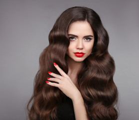 Obraz premium Beauty girl hair. Red lips and manicured nails. Beautiful model portrait with wavy hair and makeup isolated on studio grey background.