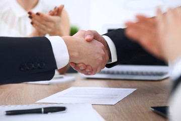 Close up of business people shaking hands at meeting or negotiation in the office. Partners are satisfied because signing contract