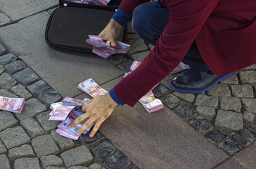 A businessman collects money from the ground