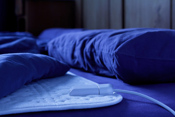 Electric heating blanket on a bed at night, thermotherapy for fibromyalgia syndrome and other rheumatic diseases
