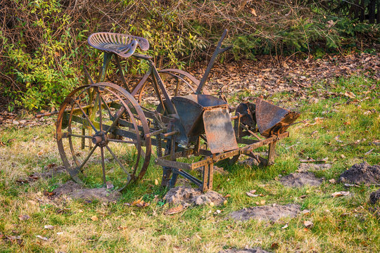 An old retro rusted farm machine plow on the ground unused