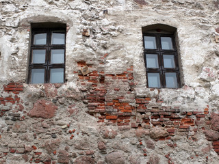 Two windows with the wooden frame in the bricks wall of the medieval house