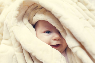 girl looking with one eye from behind the blankets