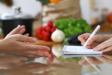 Close-up of human hands are gesticulate over a table in the kitchen. Women choosing menu or making online shopping. So much ideas for tasty cooking