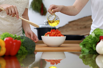 Close-up of  human hands  cooking in a kitchen. Friends having fun while preparing fresh salad. Vegetarian, healthy meal and friendship concept
