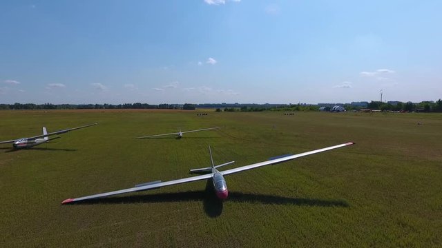 Three sports gliders plane lie on the wing in the field, aerial shooting