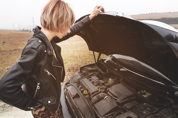 Fototapeta na wymiar Girl opening the hood of her car checks the engine oil level