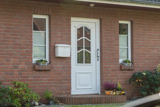 Weiße Haustür eines Hauses mit Briefkasten und Fenstern