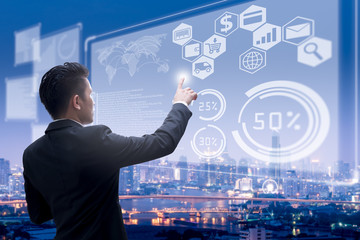 The abstract image of business man point to the hologram on the rooftop and blurred cityscape is backdrop. the concept of communication, network, business, cyber, economy and internet of things.