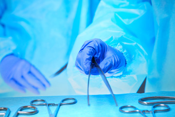 Close-up of of surgeons hands at work in operating theater toned in blue