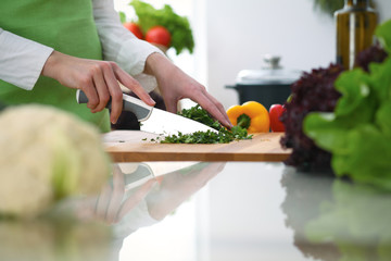 Closeup of human hands cooking vegetables salad in kitchen on the glass  table with reflection