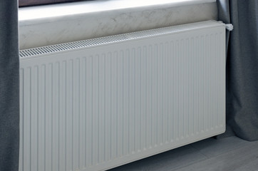Heating panel radiator in white color installed in the room.