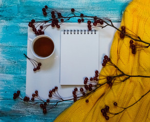 Bright background with painted blue, blue paint boards, a cup of tea, a branch with apples and sweater with copy space. Top view