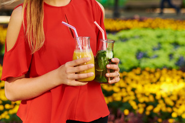 Healthy lifestyle. Unrecognizable young woman with fruit detox smoothie in summer, on green nature background. Diet, well being and weight loss concept
